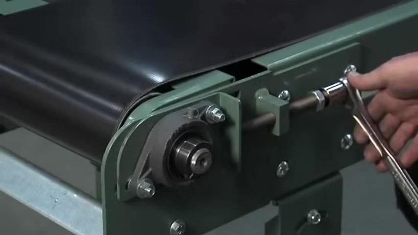 Adjusting the tension screw on the conveyor frame with a wrench
