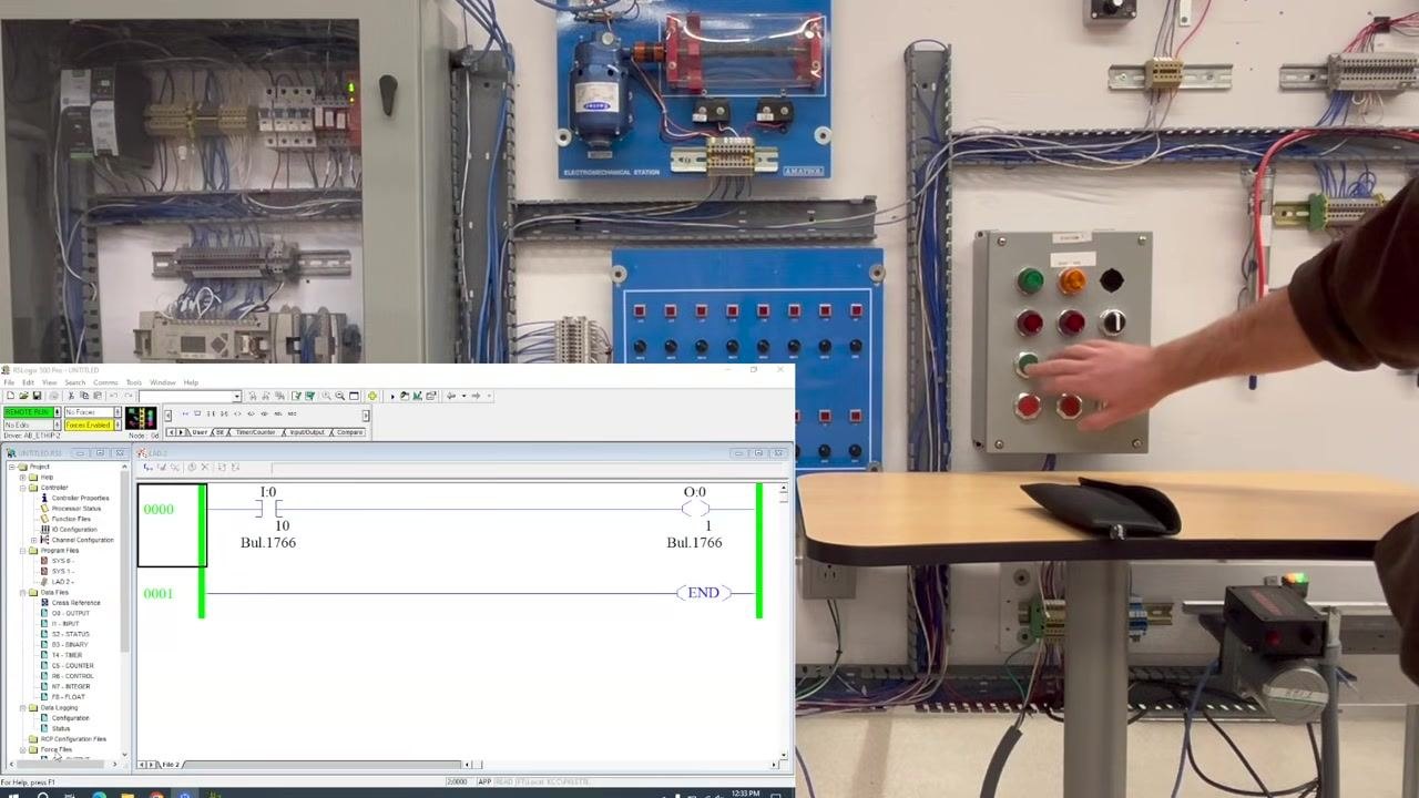 A PLC training station with multiple panels, wiring, and labeled push buttons. A note indicates an output is not working.
