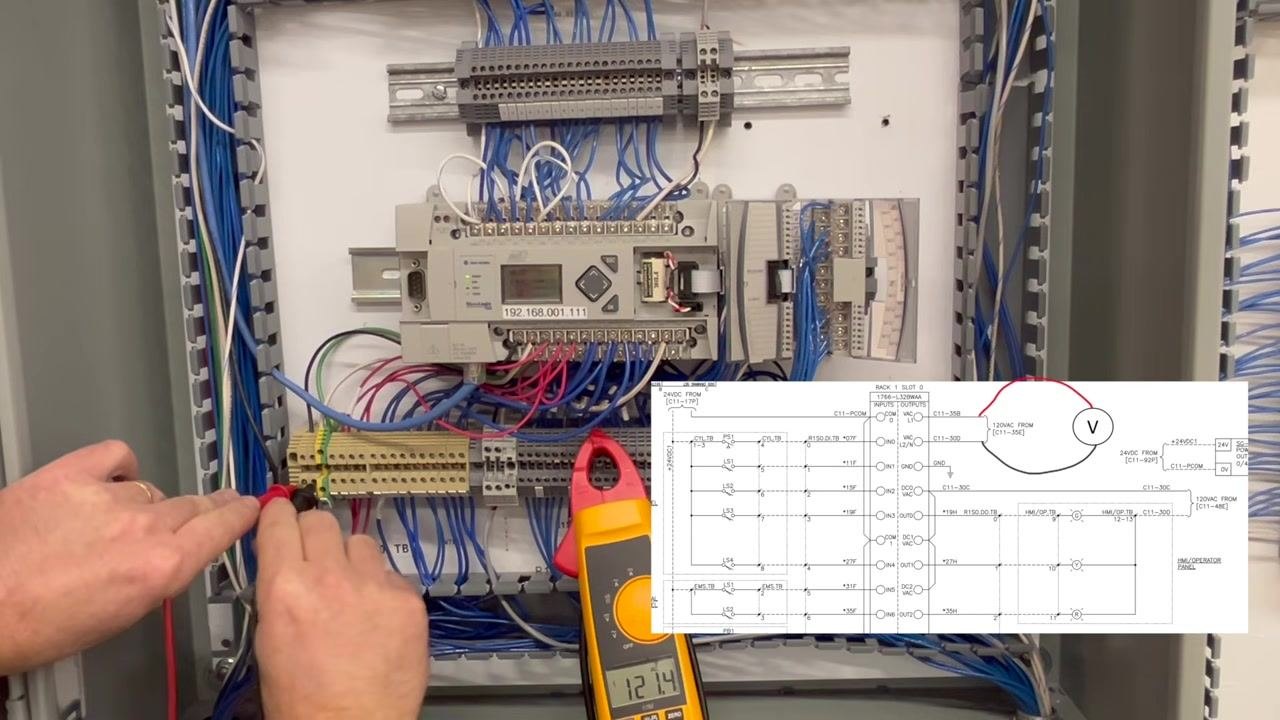 Hands holding multimeter probes to a terminal block inside the control panel. The clamp meter display reads 121.4V, with a schematic overlay showing the measurement points.