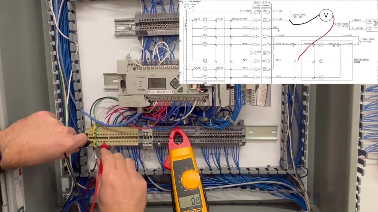 Hands holding multimeter probes to a different terminal block connection. The clamp meter display reads 0.0V, with a schematic overlay showing the new measurement points.