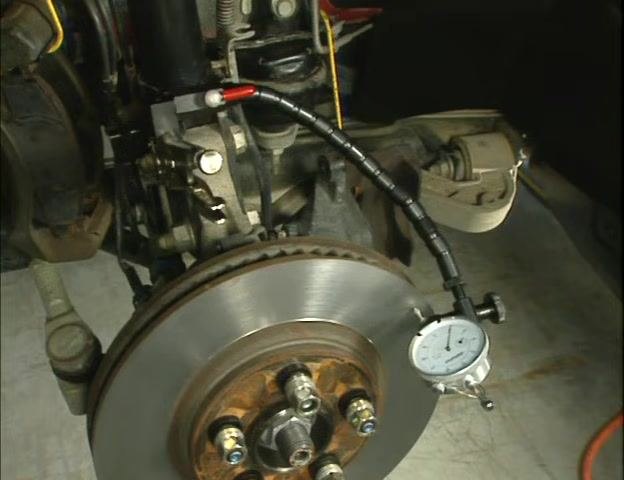 Close-up of a hand turning the red cam lever to lock the flex arm and dial indicator in place.