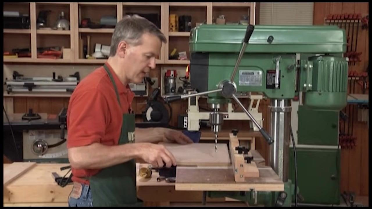 Operator positioning a marked workpiece under the drill bit using the fence for alignment