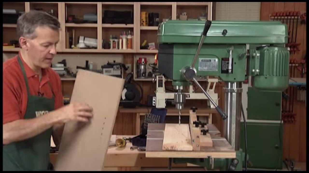 Operator holding up a workpiece with a line of drilled holes to inspect the results