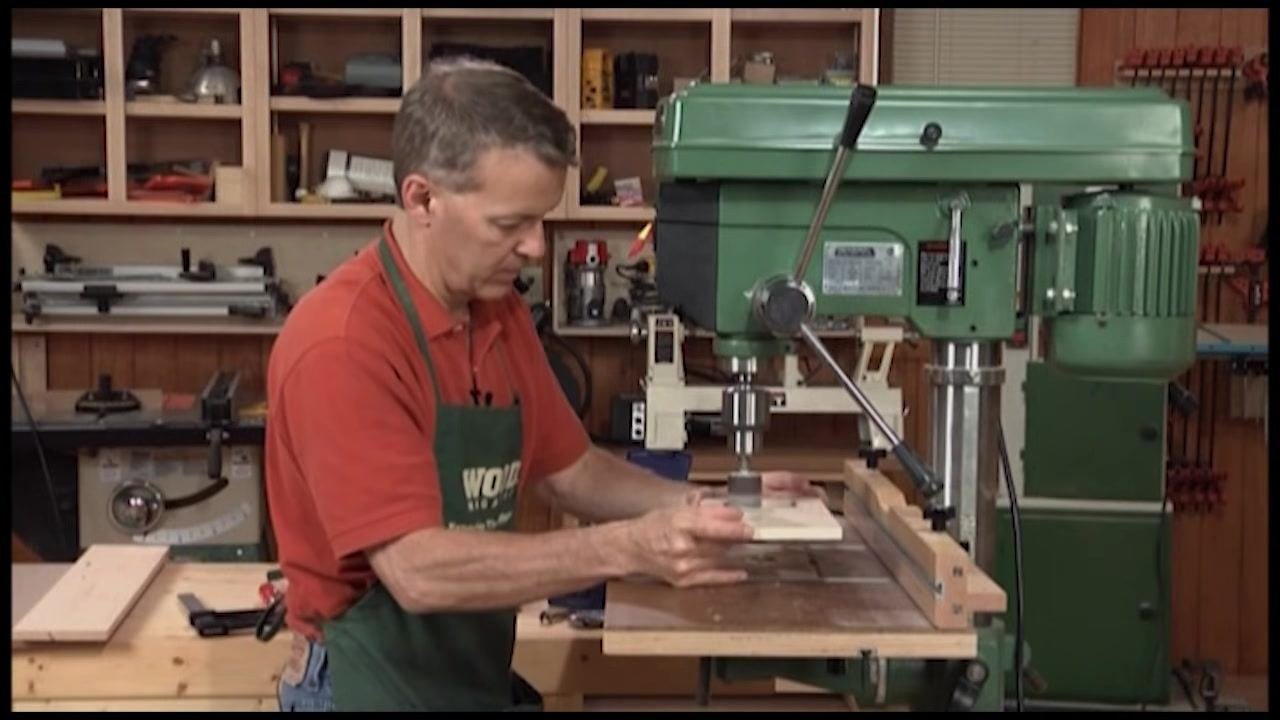 Operator holding the workpiece against the spinning drum sander to sand the inside curve