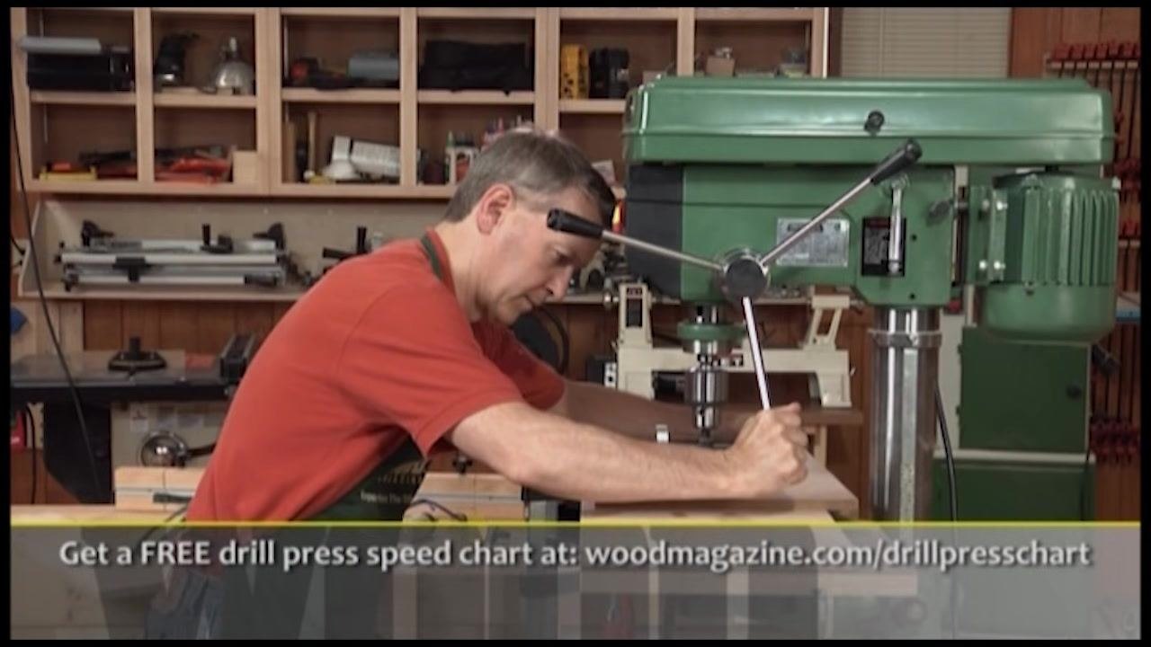 Demonstration of safe hand placement on a large board at the drill press, keeping hands away from the spinning bit