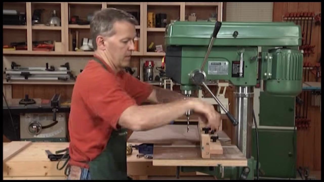 Operator adjusting and locking down a wooden fence on the drill press table