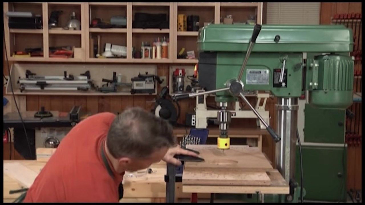 Close inspection of the clamped workpiece and hole saw setup on the drill press