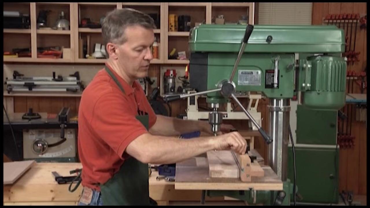 Operator extending the table wings and adjusting stop blocks for repetitive drilling tasks