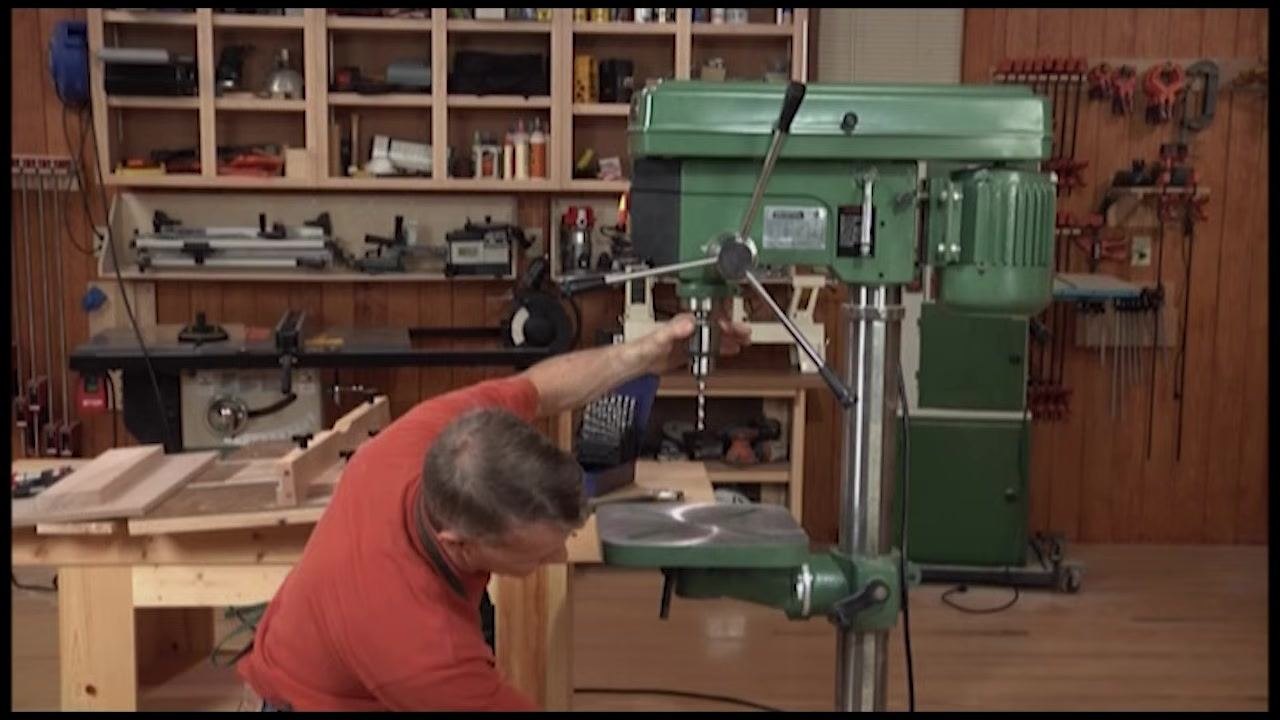 Operator adjusting the drill press table height using the geared handle on the column