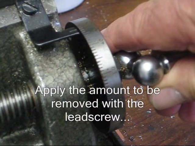Operator advancing the carriage with the leadscrew while the lathe runs and the workpiece spins.