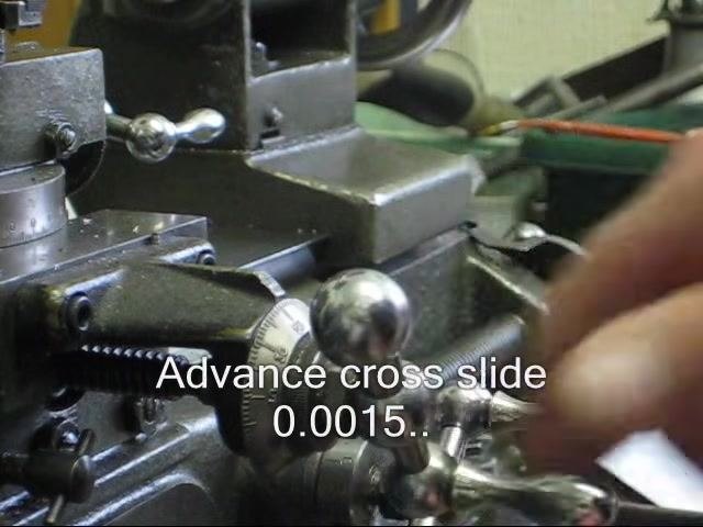 Operator's hand advancing the cross slide handwheel, with the cross slide dial visible.