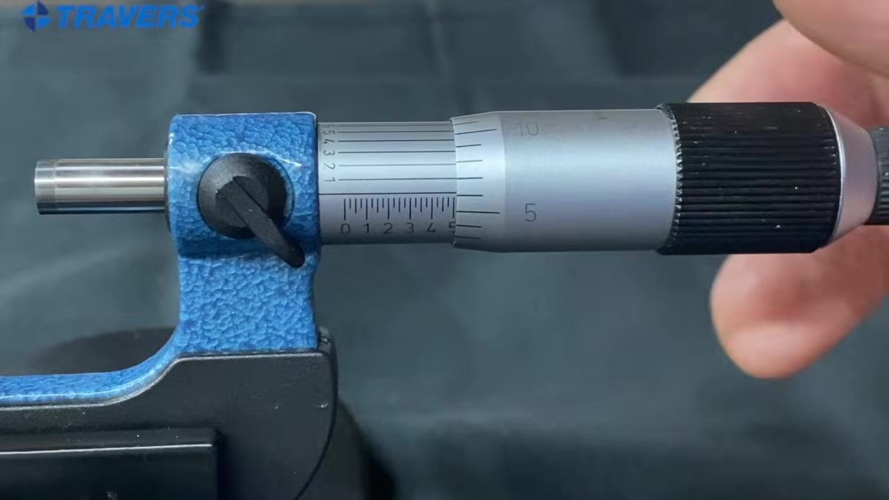 Micrometer close-up with a pen tip indicating the vernier alignment, with the sleeve and thimble scales visible.