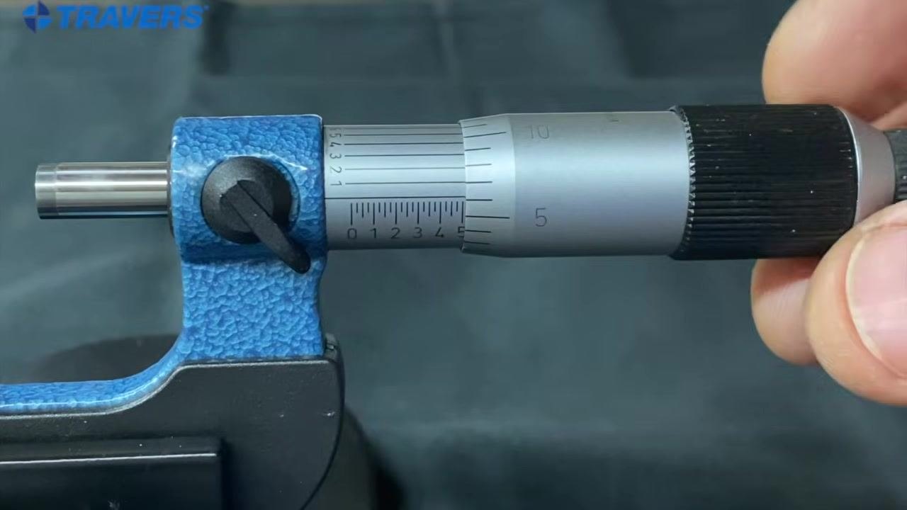 Micrometer close-up with a pen tip indicating the 9th thimble line, with the sleeve and thimble scales visible.