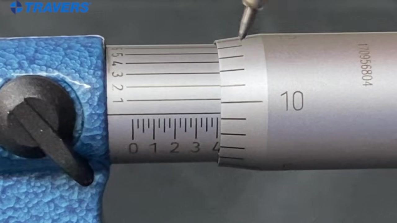 Micrometer close-up with a pen tip indicating the aligned line, with the 10 mark visible on the thimble.