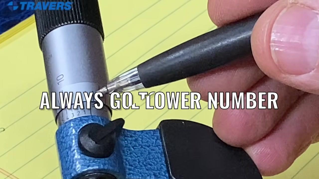 Close-up of the micrometer scale with a pen pointing at the sleeve and thimble markings.