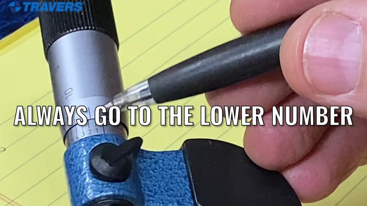Close-up of the micrometer with a pen pointing at the scale and a reminder to always use the lower number.