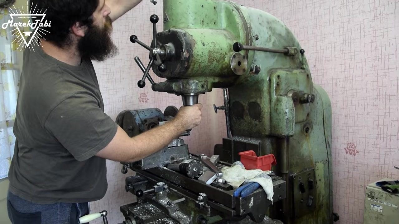 A close-up of a face mill cutter installed in the spindle, positioned above the billet in the vise, with tools and rags organized nearby.