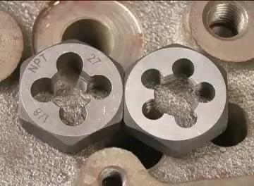 Close-up of two dies, one with the bottom side showing the marking "NPT 1/8 27" facing up