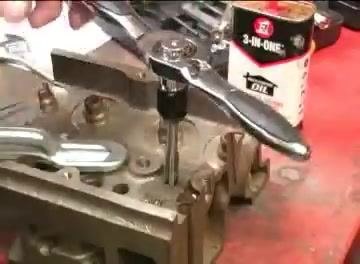 A ratcheting tap handle positioned above a threaded hole, with a can of 3-IN-ONE oil on the workbench nearby