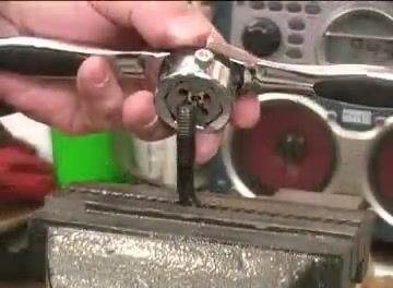 A die being started onto a rod held in a vise, using a die handle to turn it