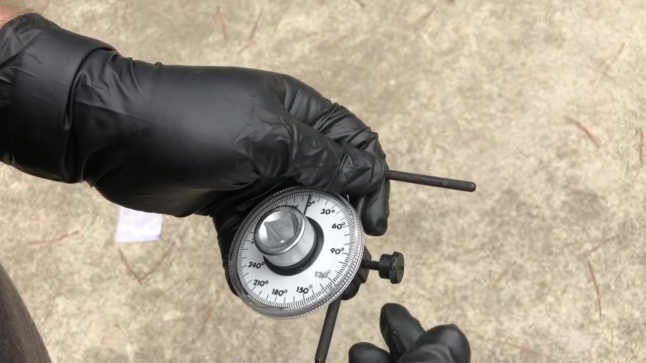Gloved hands holding the gauge with the retaining bar attached, ready for use