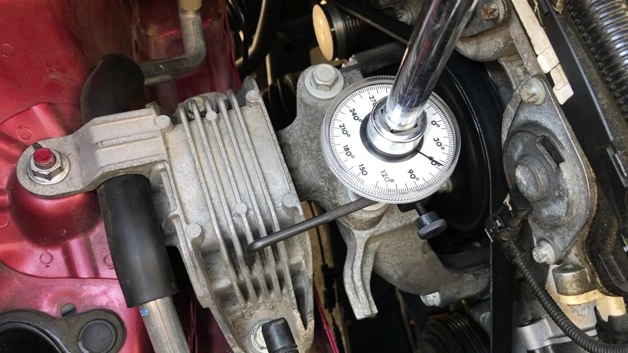 Torque angle gauge set at exactly 60 degrees, attached to a bolt with the retaining bar braced against an engine component