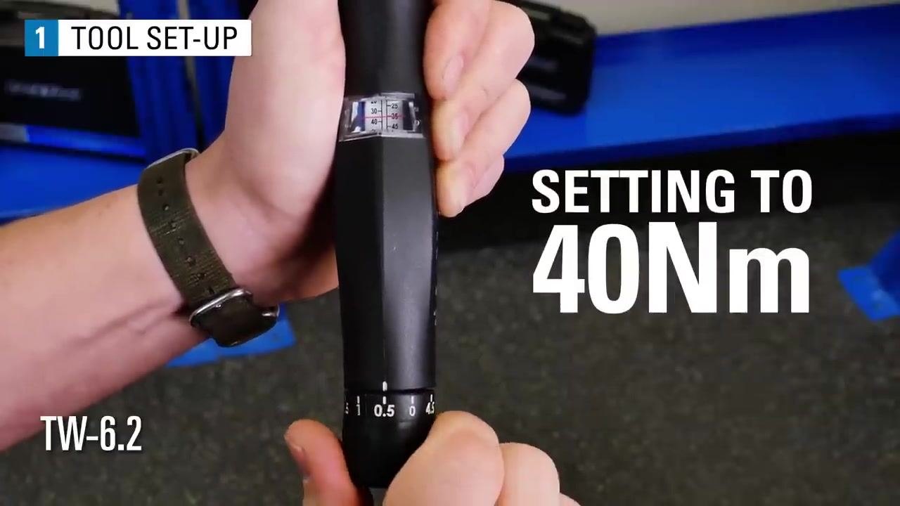 A hand holds the TW-6.2 torque wrench with the scale window showing the red line at 40 Nm and the dial reading zero.