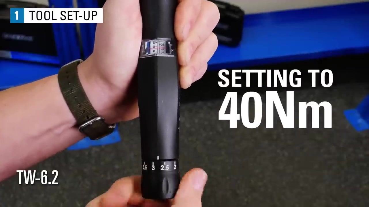 A hand adjusts the TW-6.2 torque wrench, turning the dial while the scale window shows the red line approaching 40 Nm.