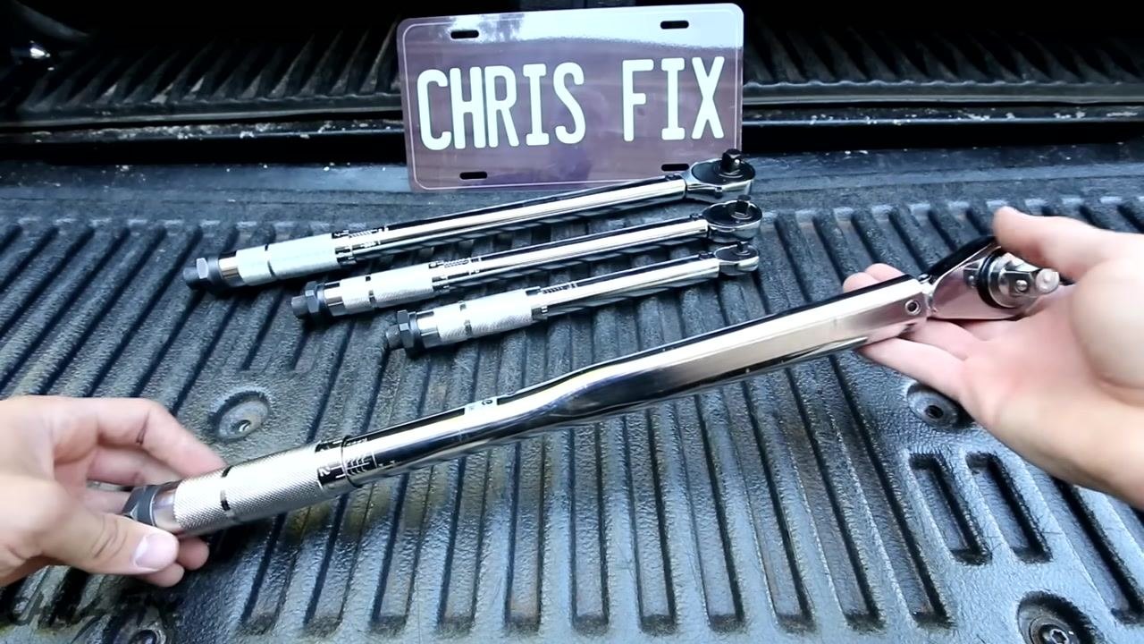 Close-up of hands adjusting the handle of a torque wrench to the lowest setting, with the scale and numbers clearly visible