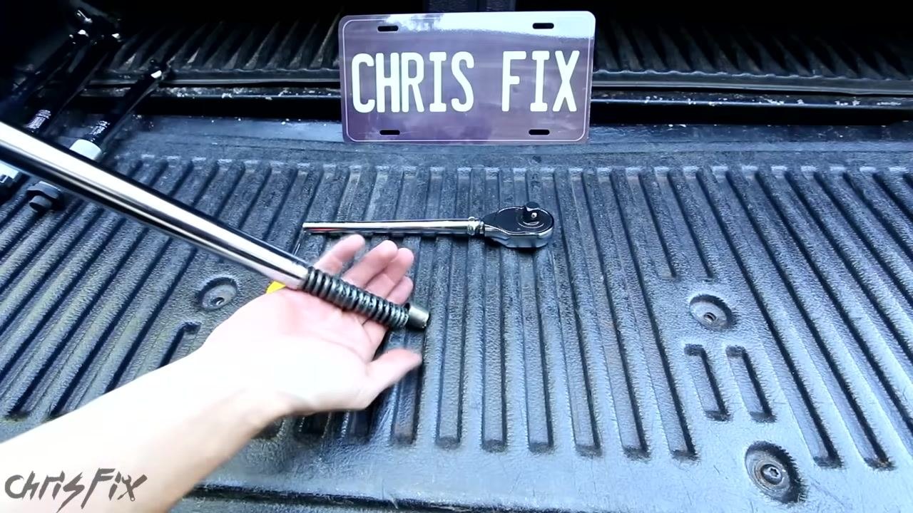 A disassembled torque wrench showing the internal spring and ratchet mechanism, with a "CHRIS FIX" plate in the background
