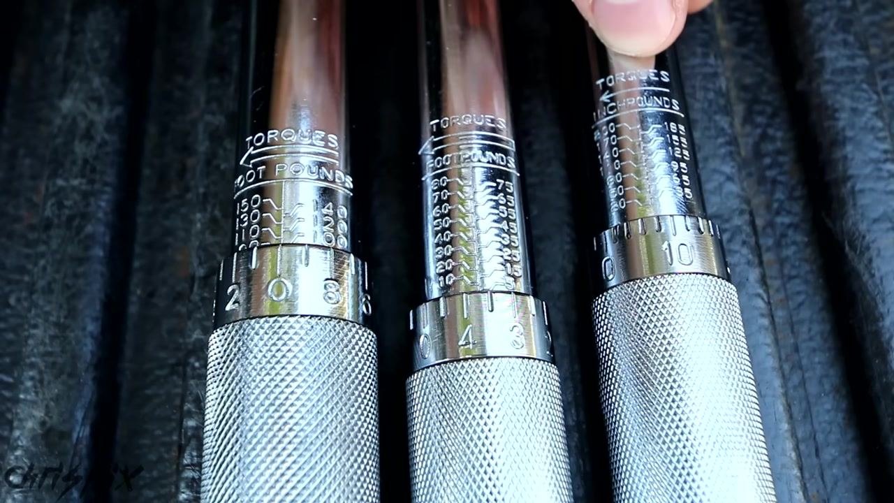 A hand points to a set of three torque wrenches and a breaker bar laid out on a truck bed, with a "CHRIS FIX" license plate in the background.