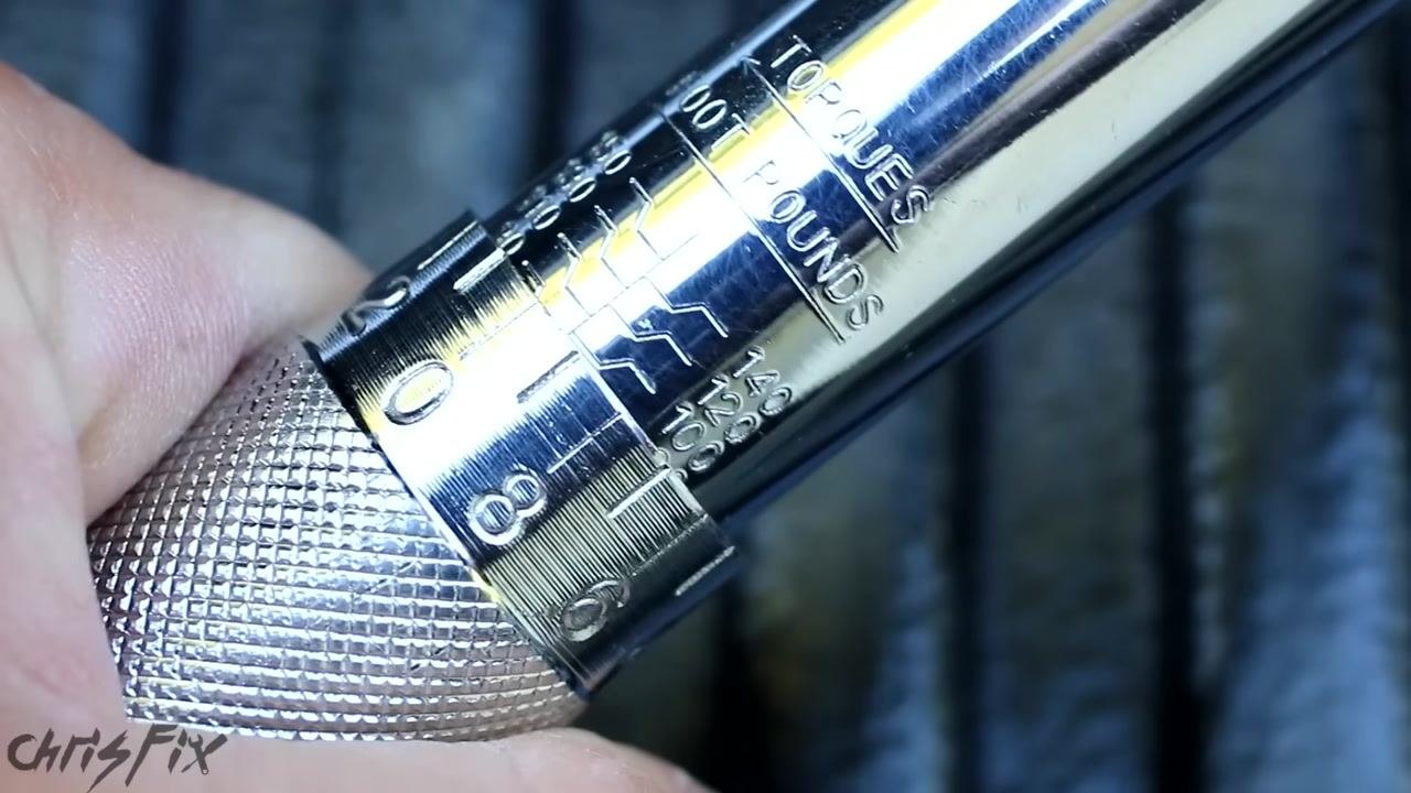 Close-up of a torque wrench handle being rotated, with the scale visible and a hand adjusting the setting