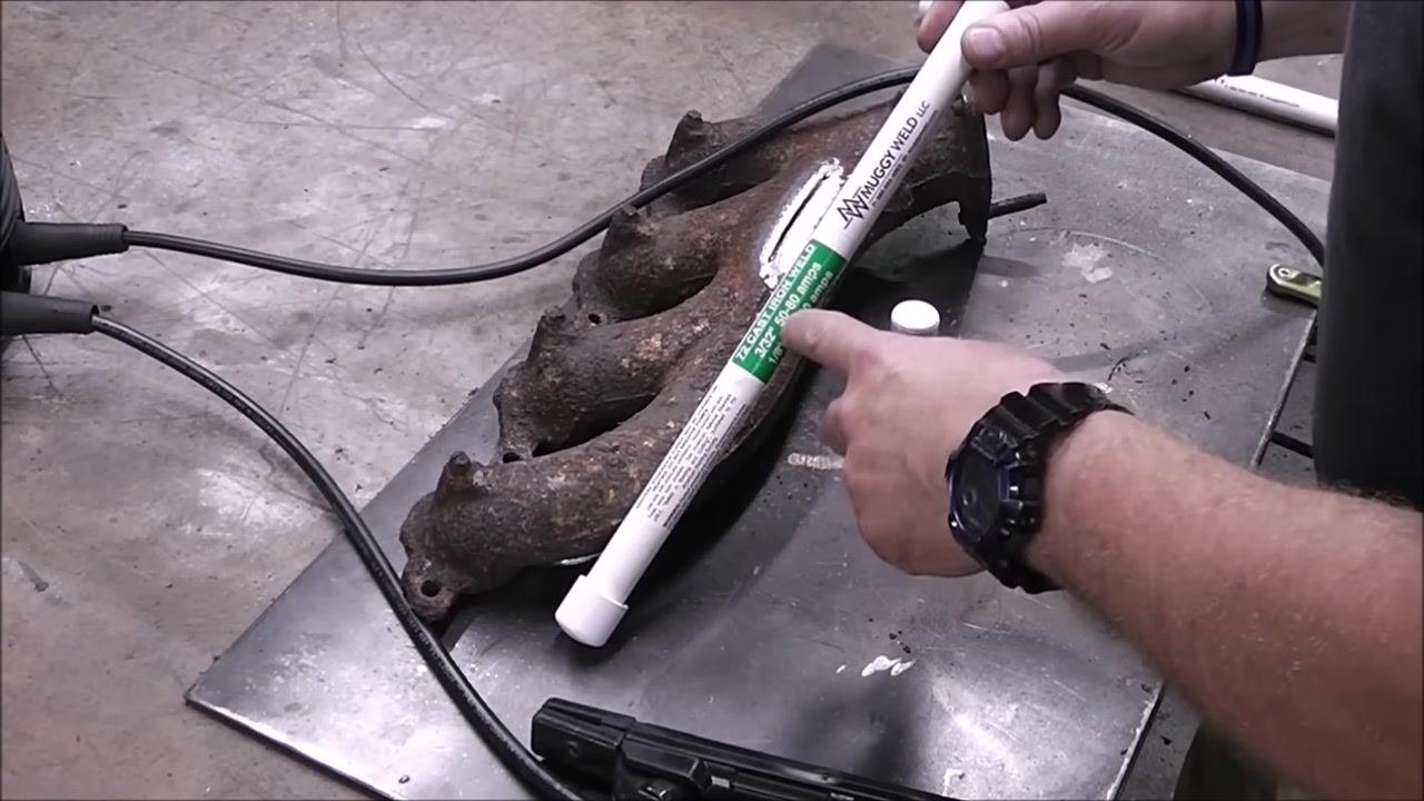 A person positions the rod on the cast iron part, preparing to weld. The workbench and welding setup are visible.