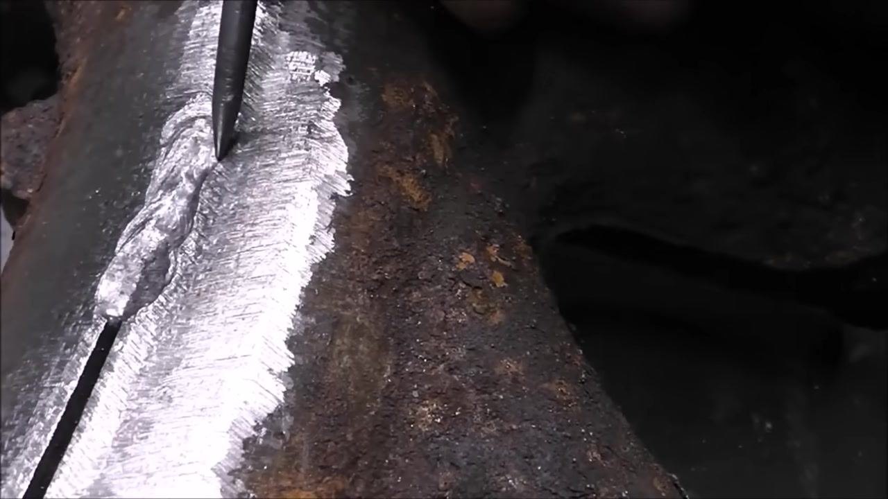 Close-up of a cast iron part with a visible weld bead and slight undercut along the edge. The area is ground clean, and the rest of the part is rusty.