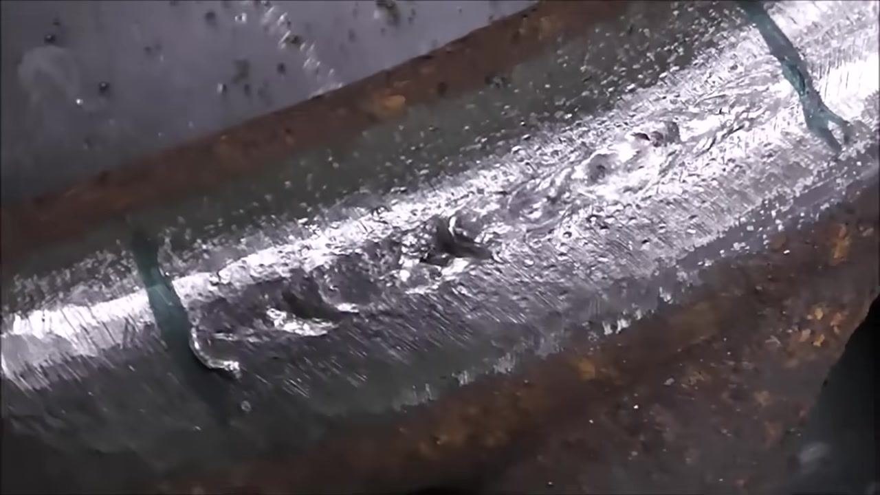 Close-up of the cast iron part with the electrode in contact with the weld area, showing the correct manipulation technique.