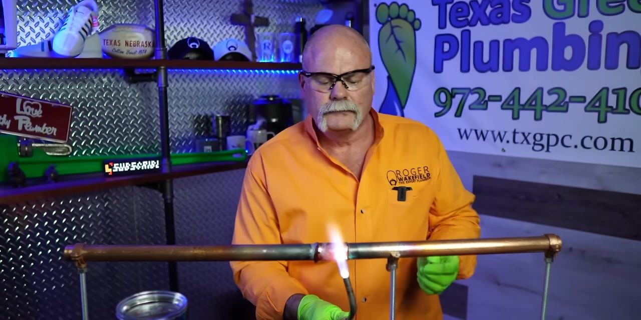 A person inspects a soldered joint from a different angle, using the torch for touch-up if needed.