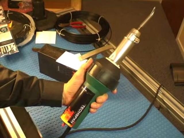A rotary tool being used to cut a V-groove at the end of a crack in a black plastic part