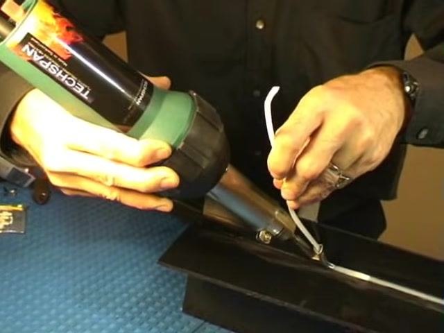 Close-up of the welding nozzle and rod in action, with the rod melting and fusing into the joint