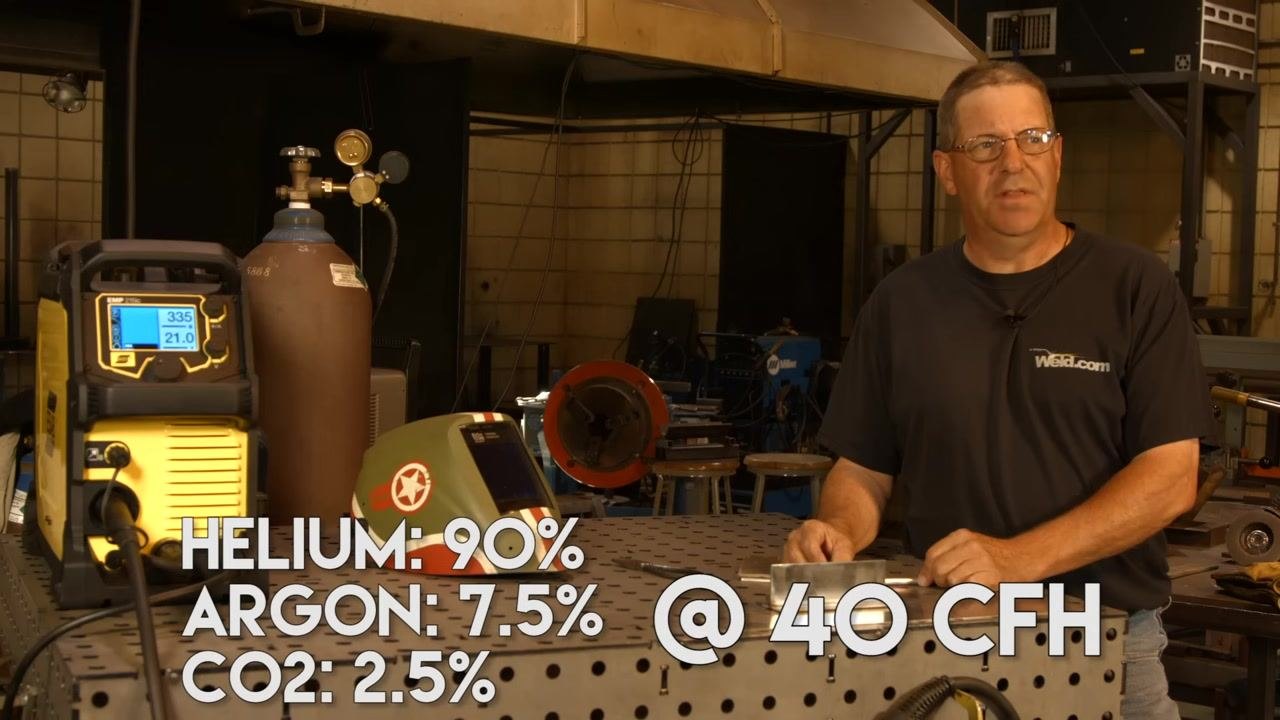 Welding machine and gas cylinder with an on-screen overlay showing Helium 90%, Argon 7.5%, CO2 2.5%.