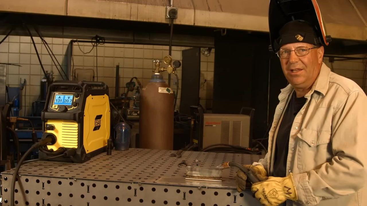 Welding gun positioned at the corner of a stainless steel fillet joint, demonstrating the technique of pulling back into the fillet to terminate the weld.