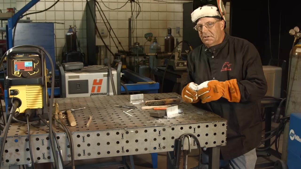 At the table with the welding machine showing 85A/52.0V, tools, and metal pieces, examining the effect of aluminum softness on the ripple pattern.