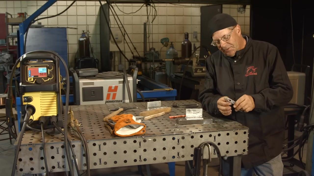Using pliers to remove residue from the electrode or workpiece, with a close-up of hands and tools and the cleaned joint on the table.