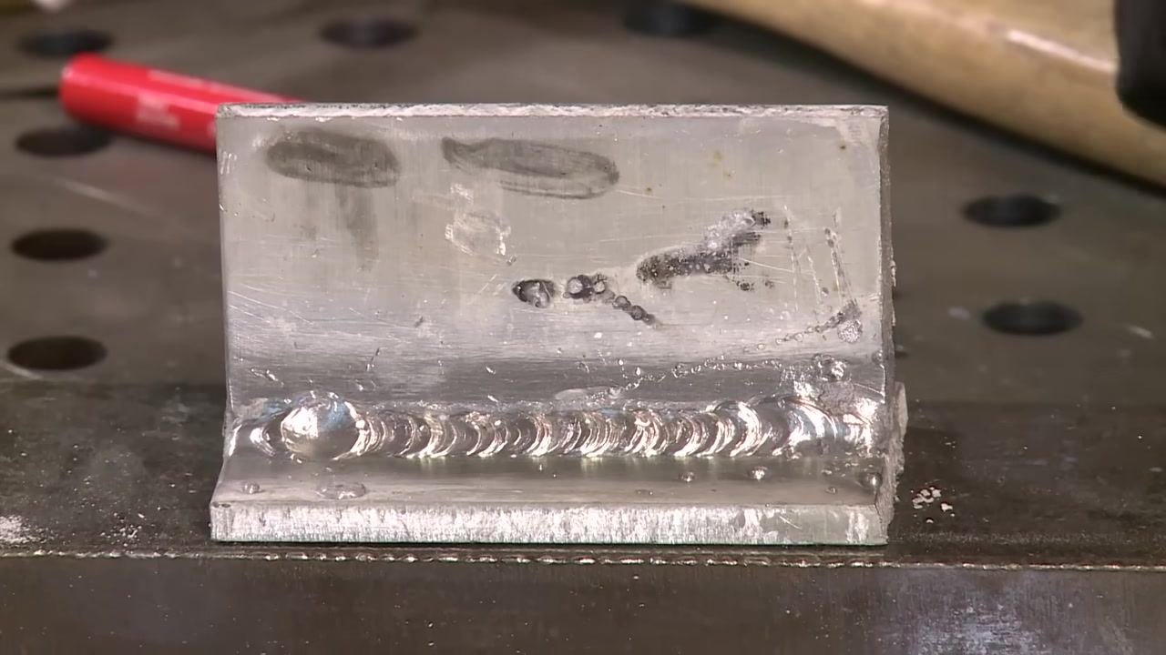 Close-up of the cleaned welded joint, with the weld bead and surface details clearly visible and tools in the background.