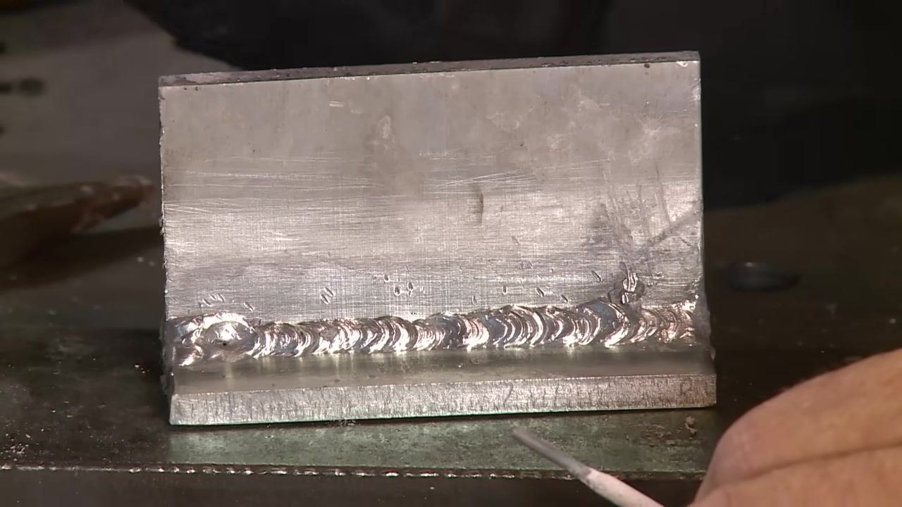Aluminum weld joint with a crater at the termination point, a rod pointing to highlight the defect.