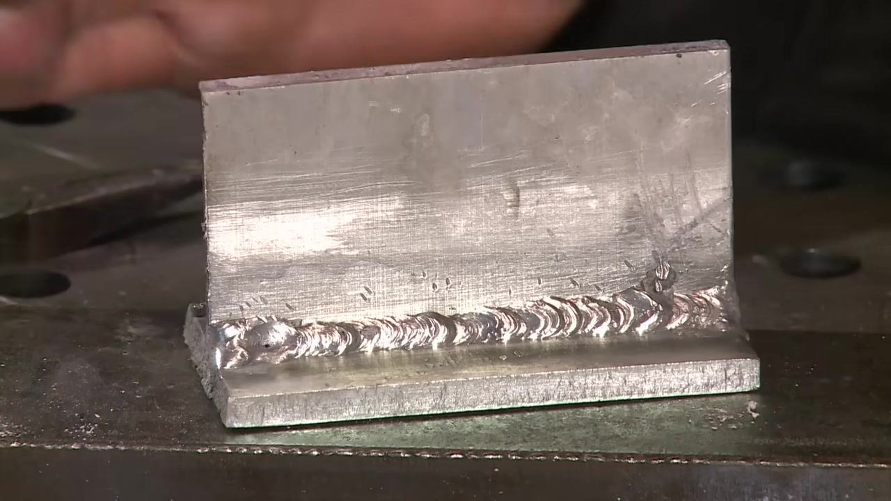 Instructor facing camera in workshop, encouraging viewers to subscribe for more welding videos