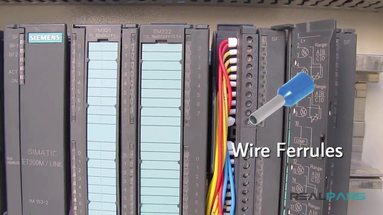 Close-up of Siemens PLC modules with colored wires (yellow, red, blue) connected to the front connector using white wire ferrules.