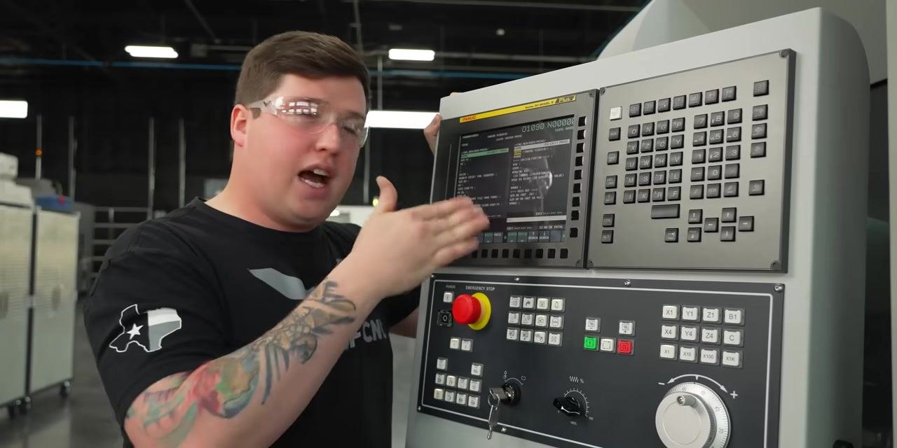 Operator at CNC control panel explaining the process, pointing at the screen