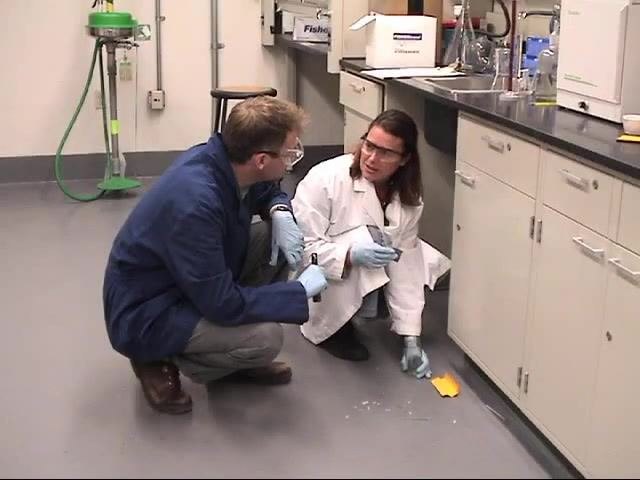 A laboratory worker places mercury waste into a secondary container to prepare it for pickup.