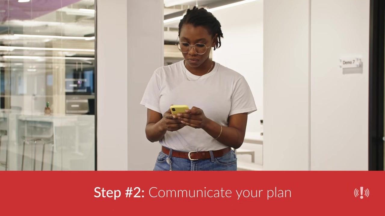 Employee in an office using a smartphone to receive fire drill communications.