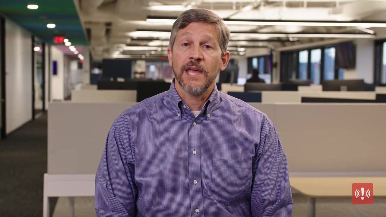 A person in a purple shirt in an office setting, with on-screen text encouraging viewers to access more employee safety tutorials.